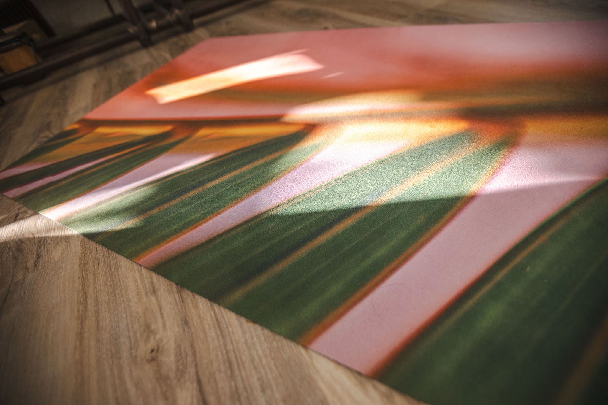 Pink and green yoga mat on a wooden floor
