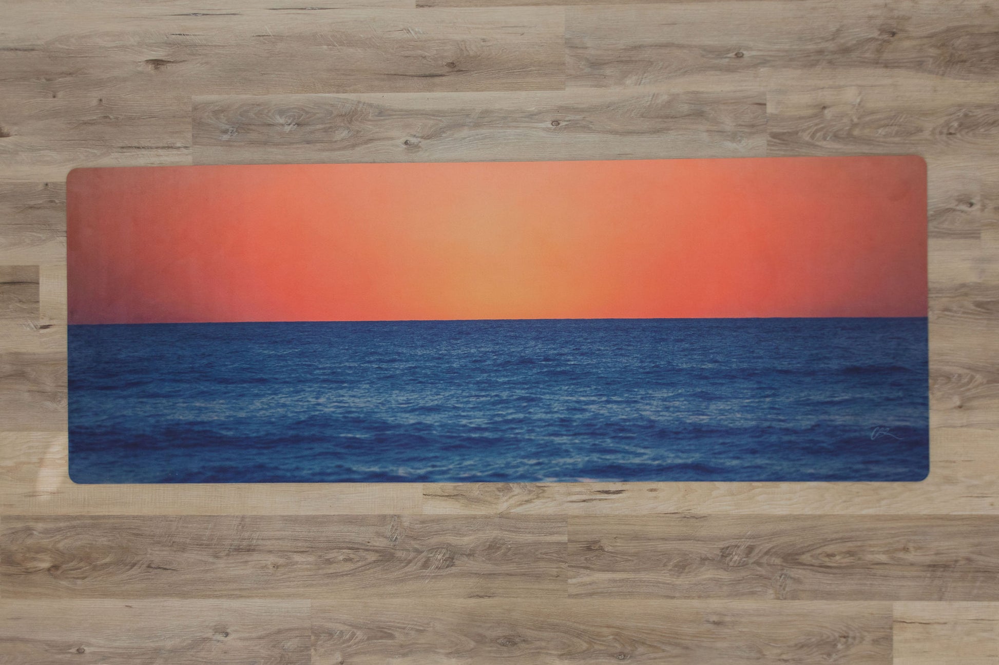 Yoga mat with a sunset design on a wooden floor
