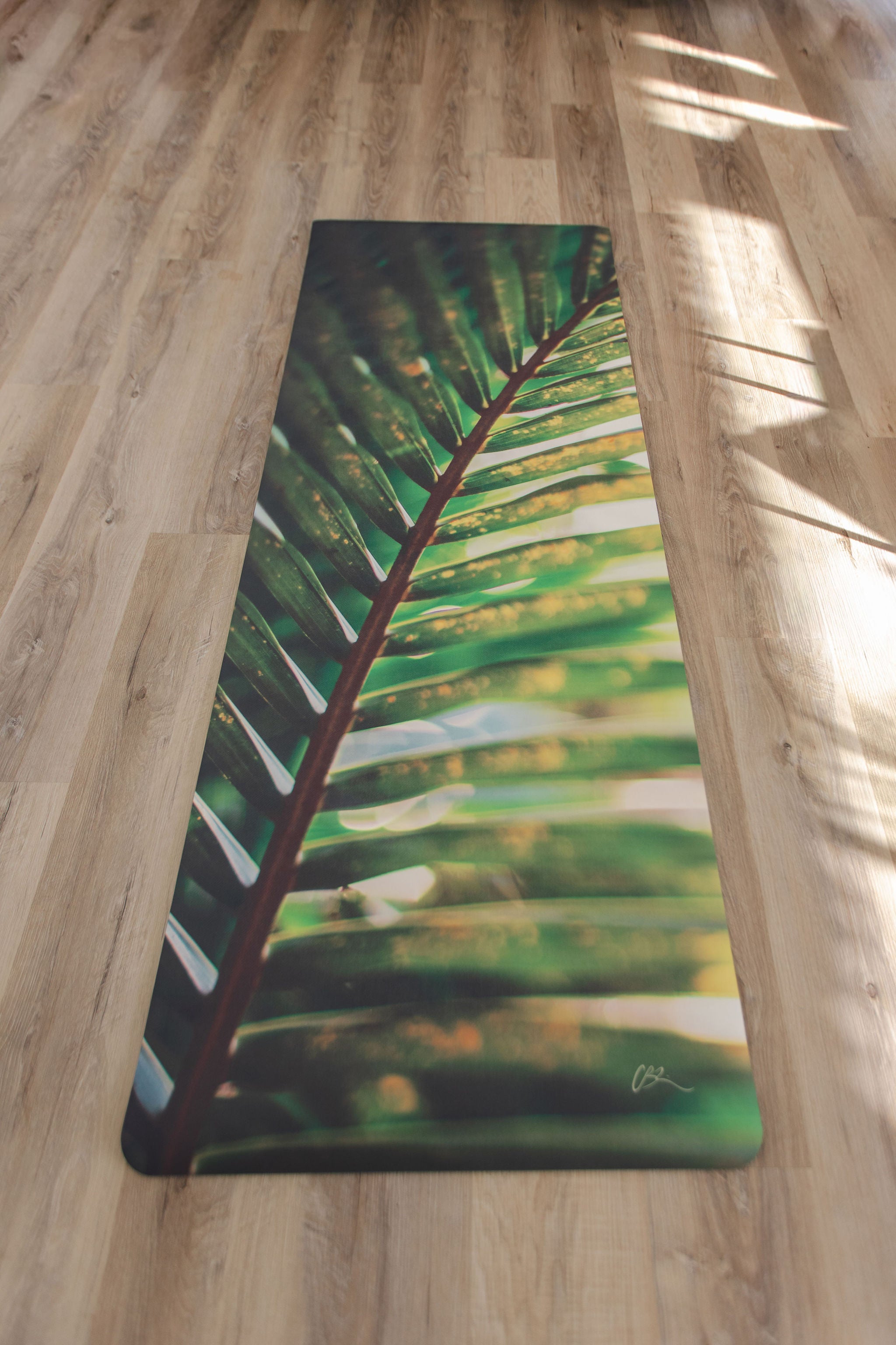 Yoga mat with green leaf design on a wooden floor