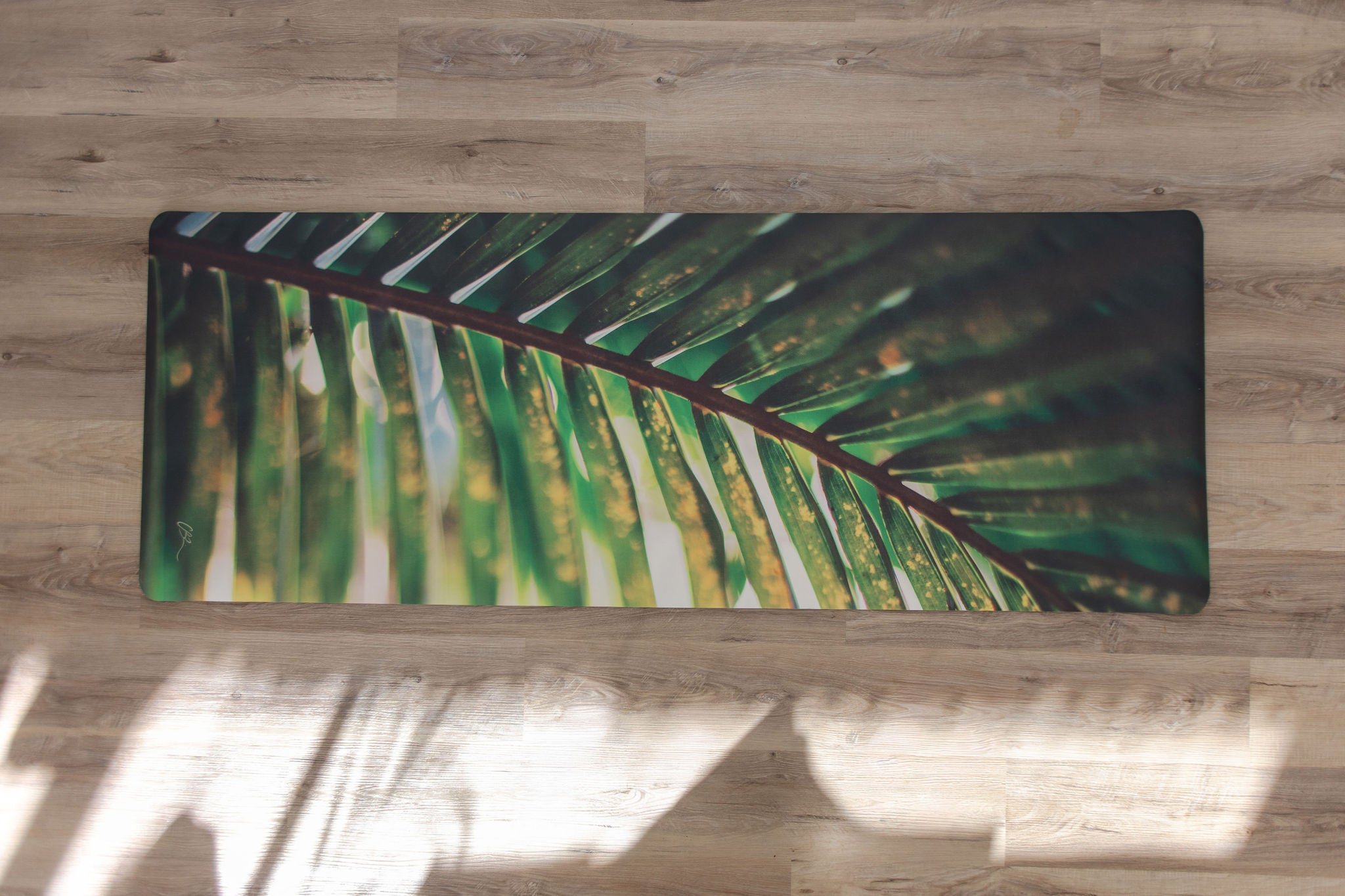 Yoga mat with palm leaf design on a wooden floor