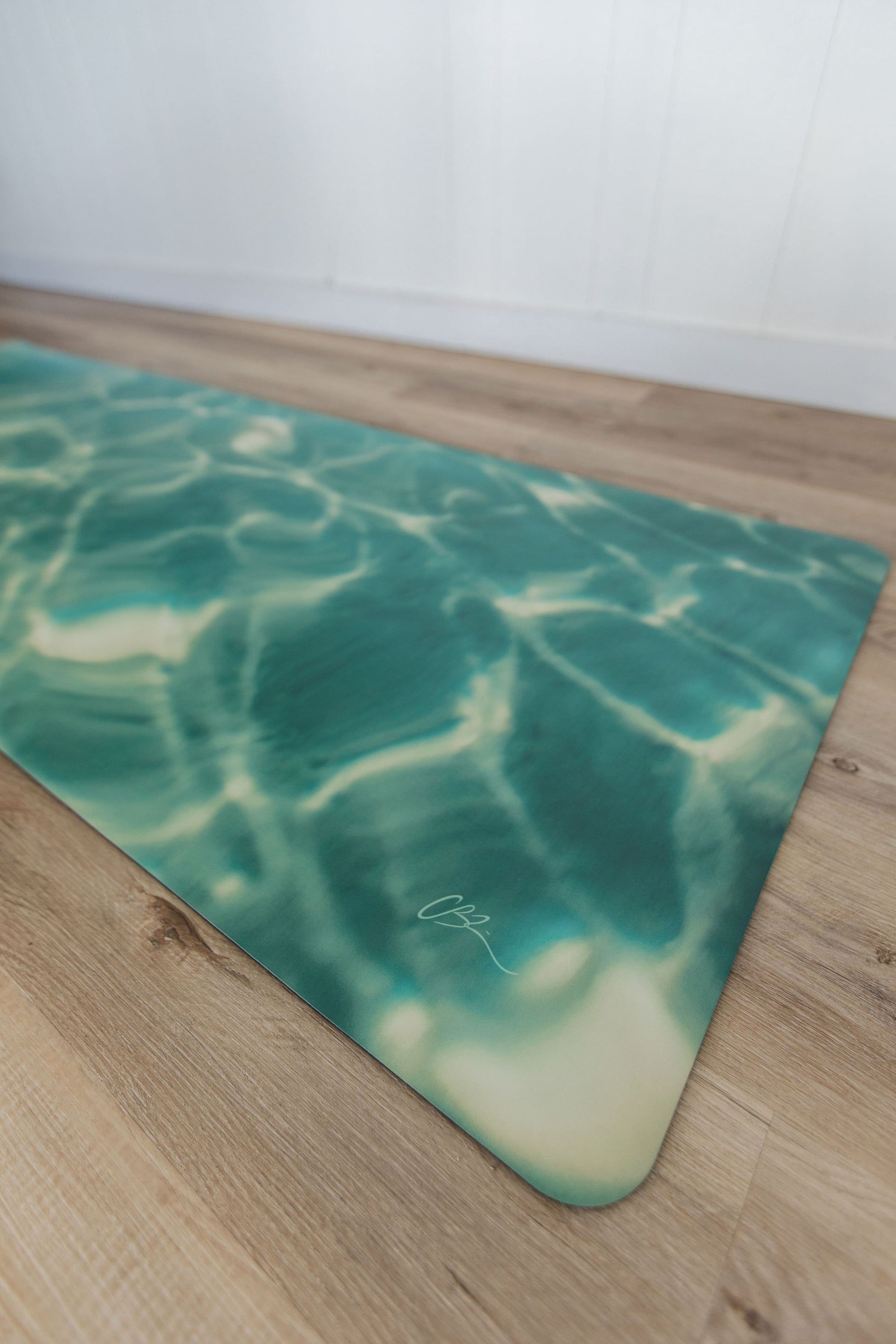 Green and white patterned yoga mat on a wooden floor