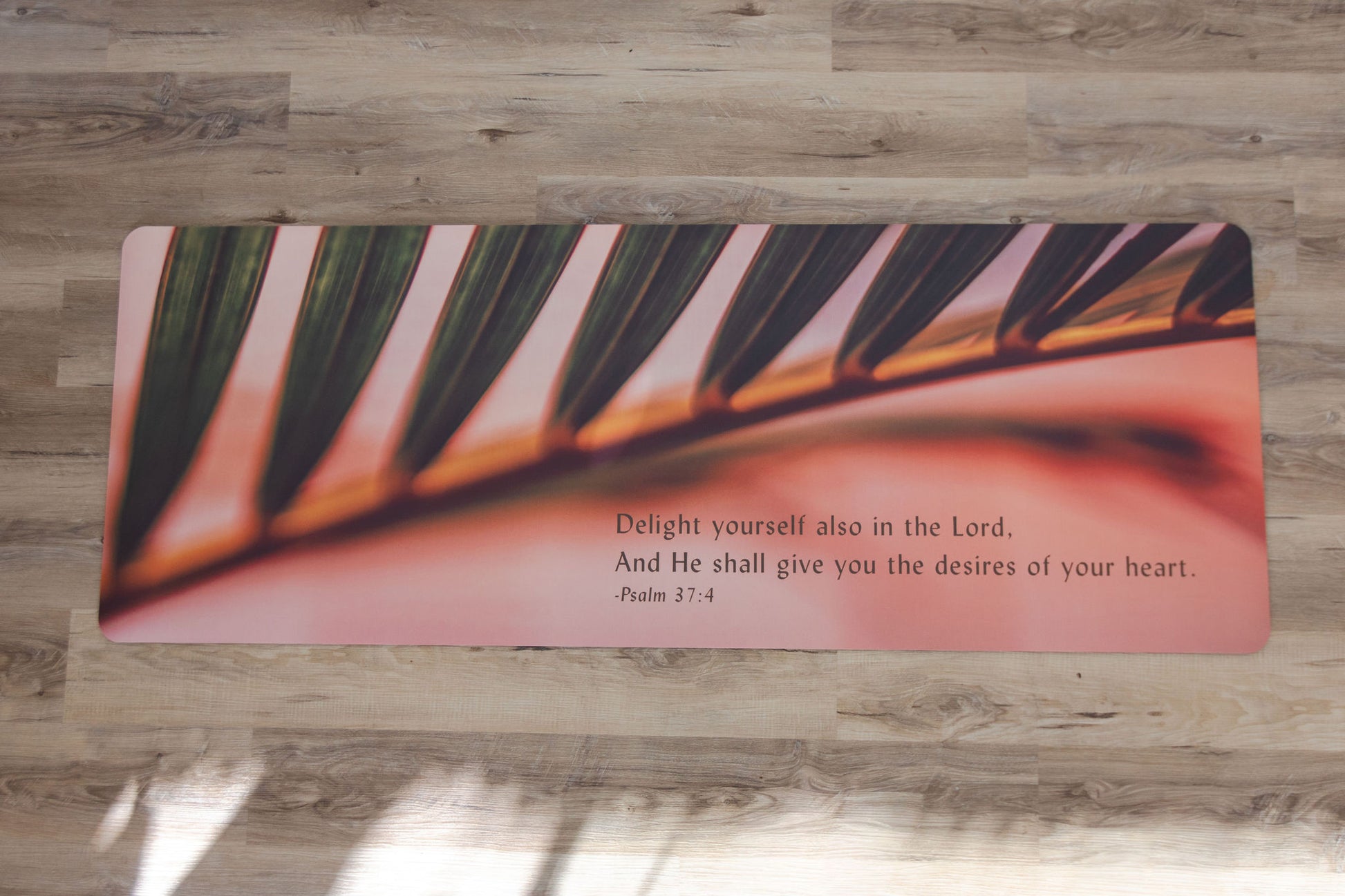 Yoga mat with a leaf design and inspirational quote on a wooden floor