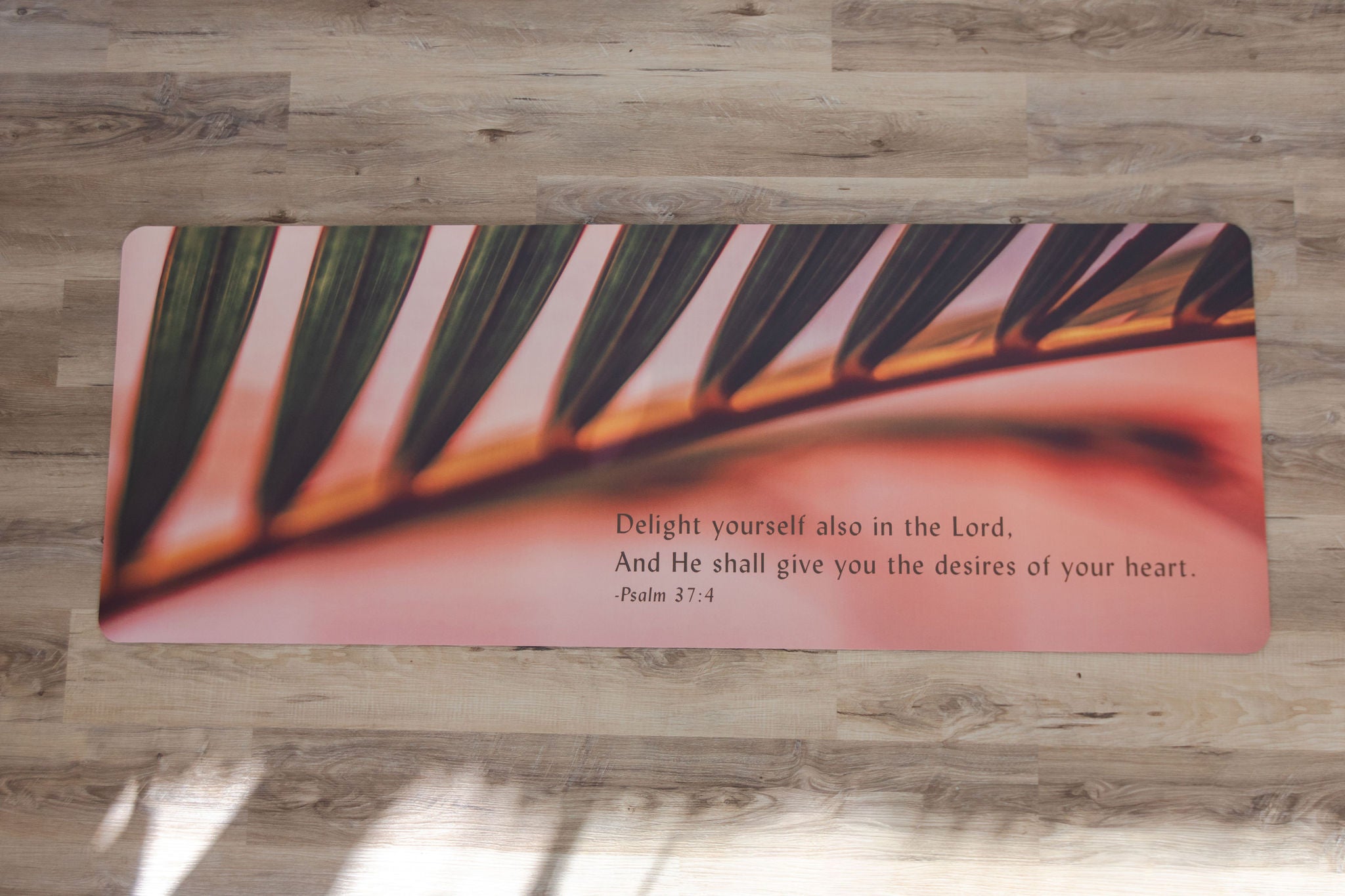 Yoga mat with a leaf design and inspirational quote on a wooden floor