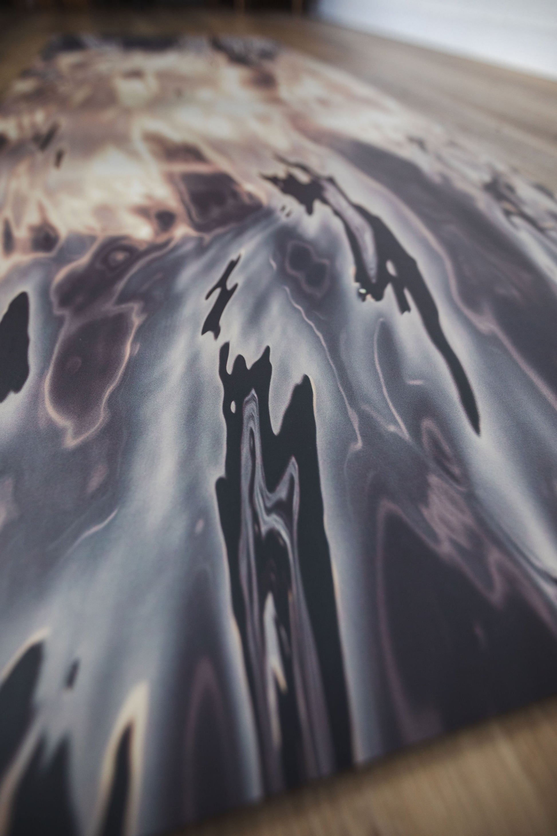Abstract art piece with dark and light color patterns on a textured surface.
