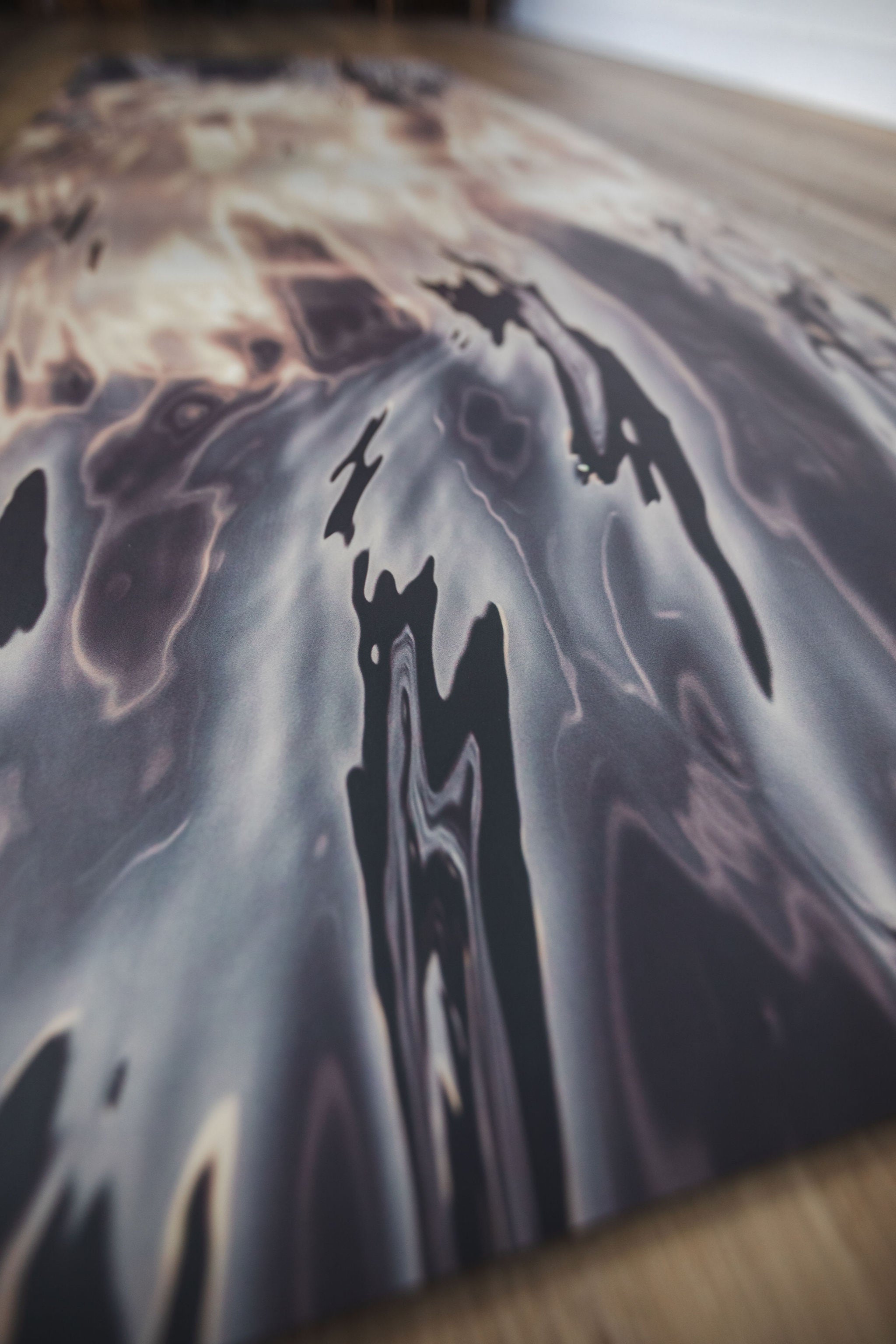 Abstract art piece with dark and light color patterns on a textured surface.