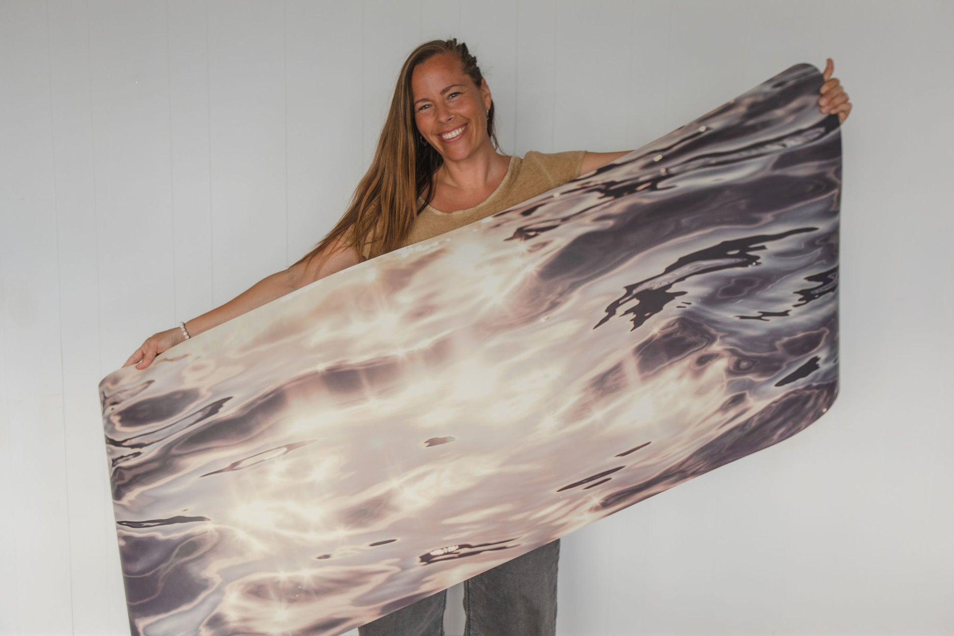 Woman holding a large piece of marbled fabric against a plain background