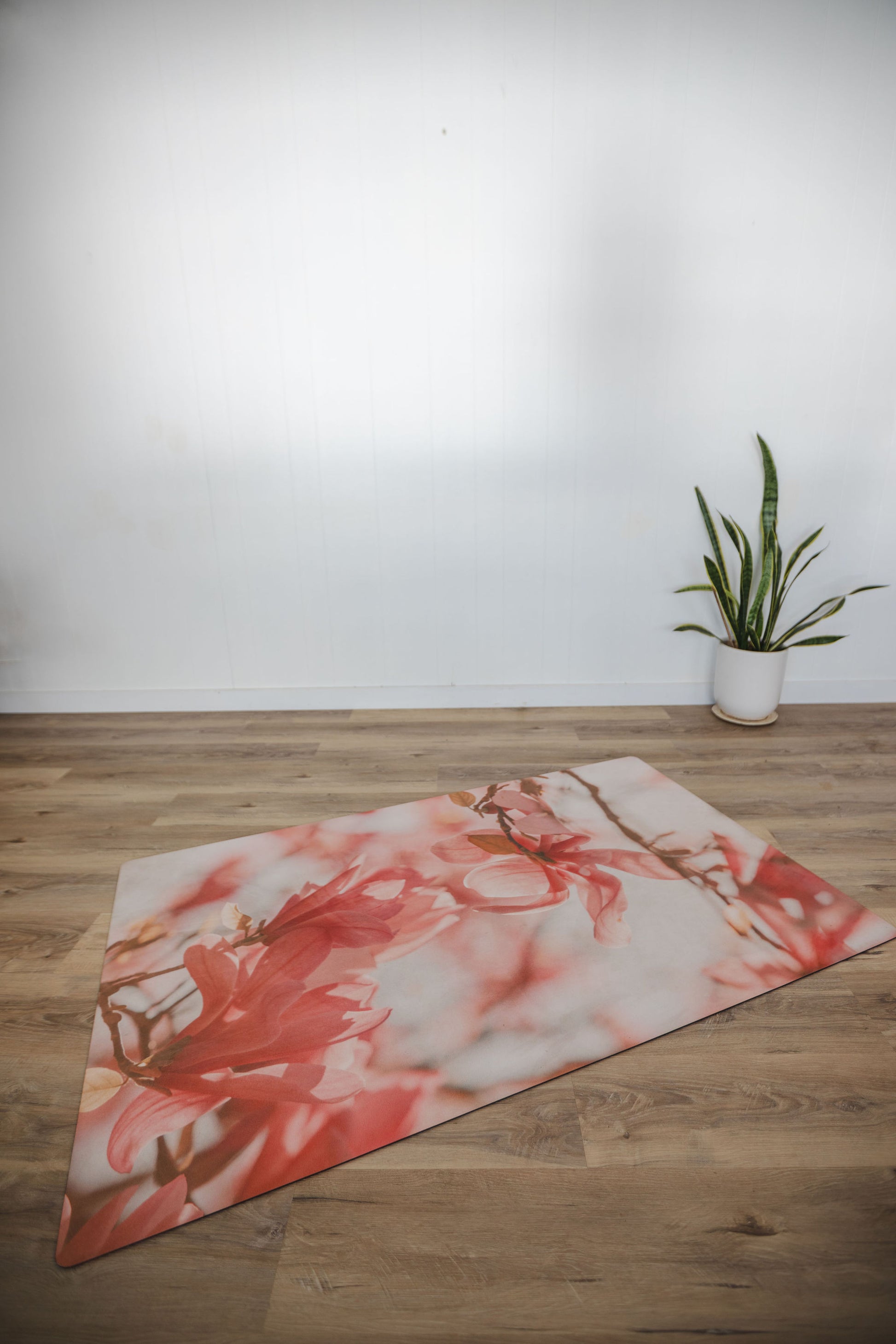 Yoga mat with floral design on a wooden floor next to a plant