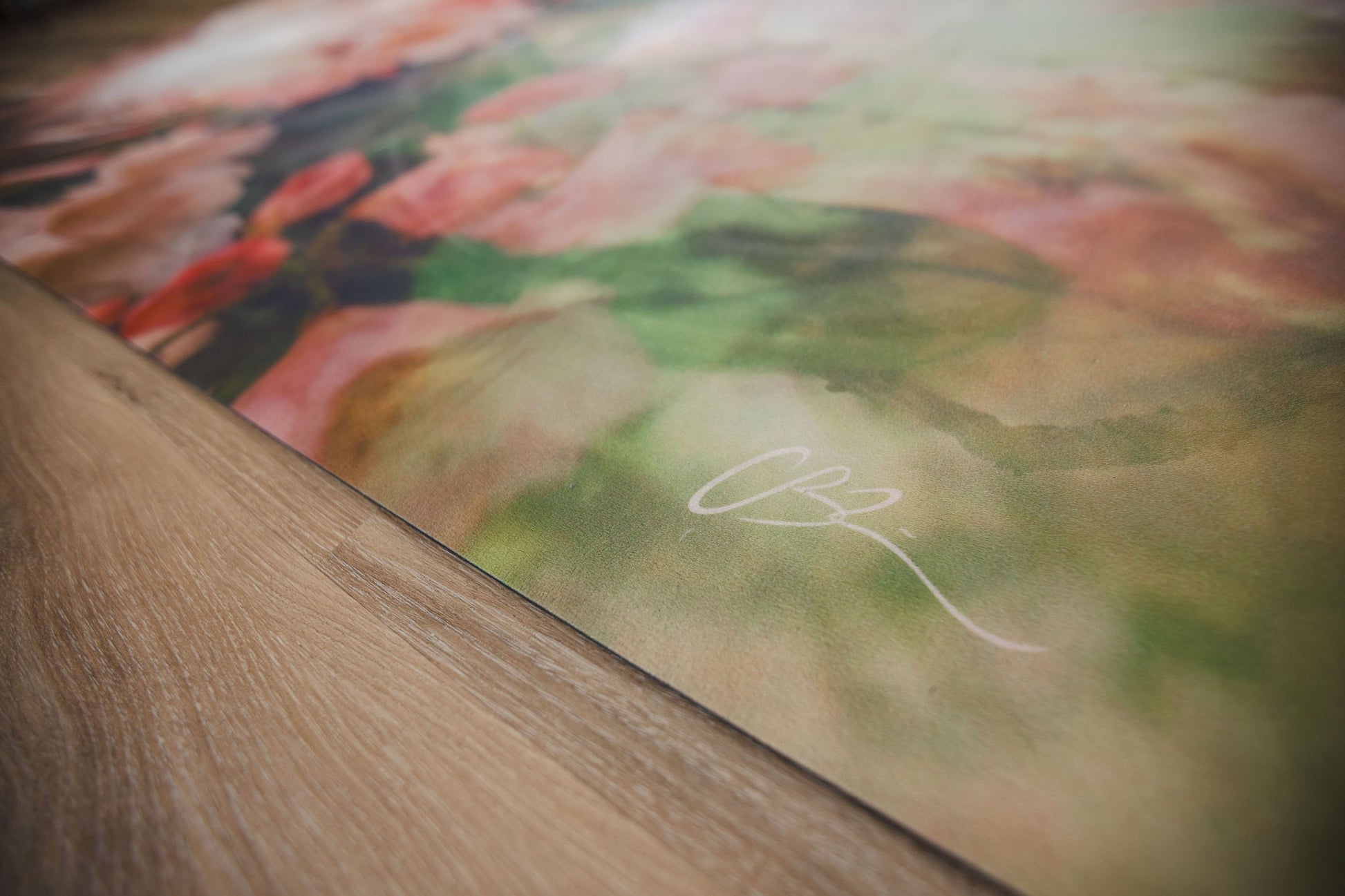 Close-up of a floral painting with a signature on a wooden surface