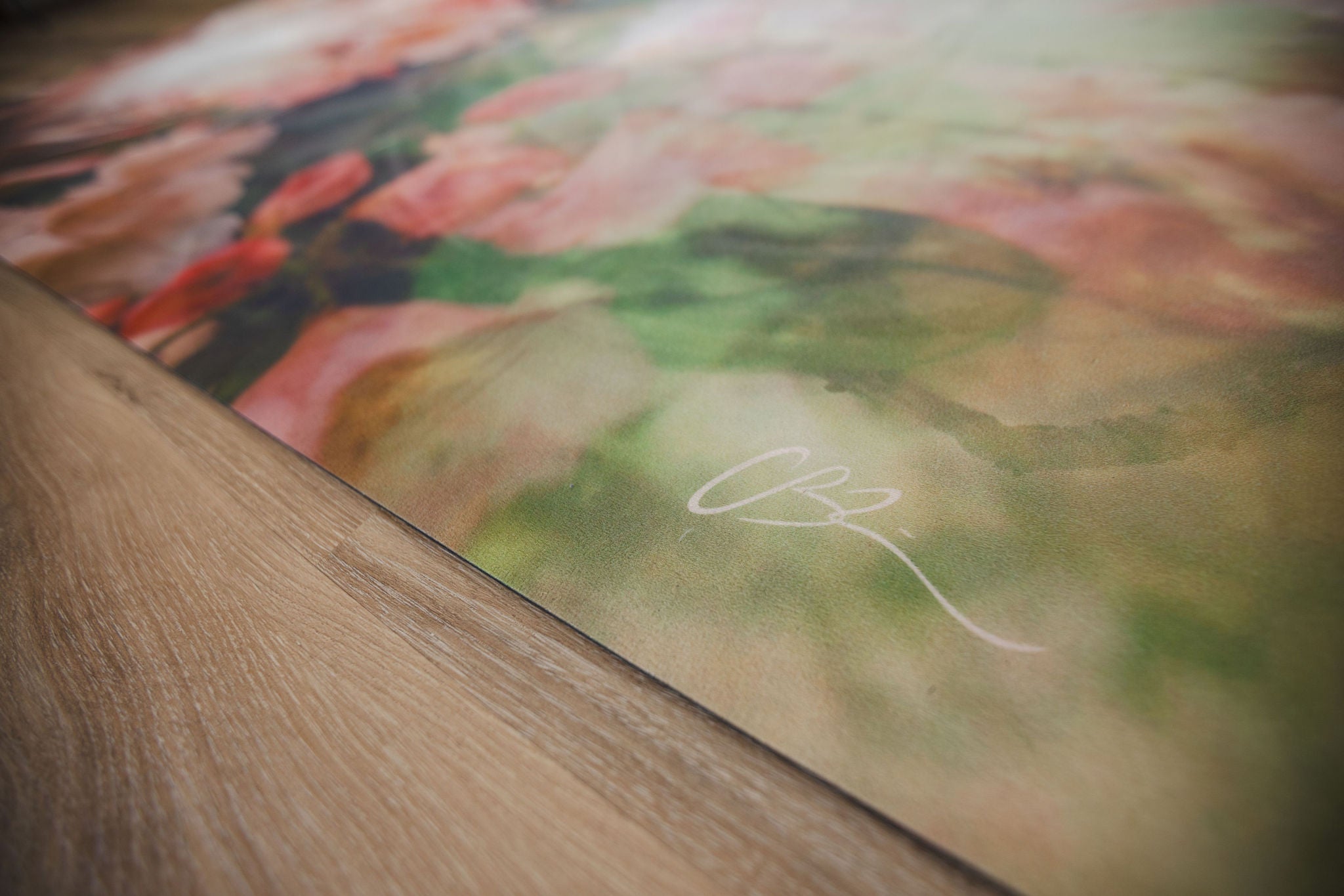 Close-up of a floral painting with a signature on a wooden surface