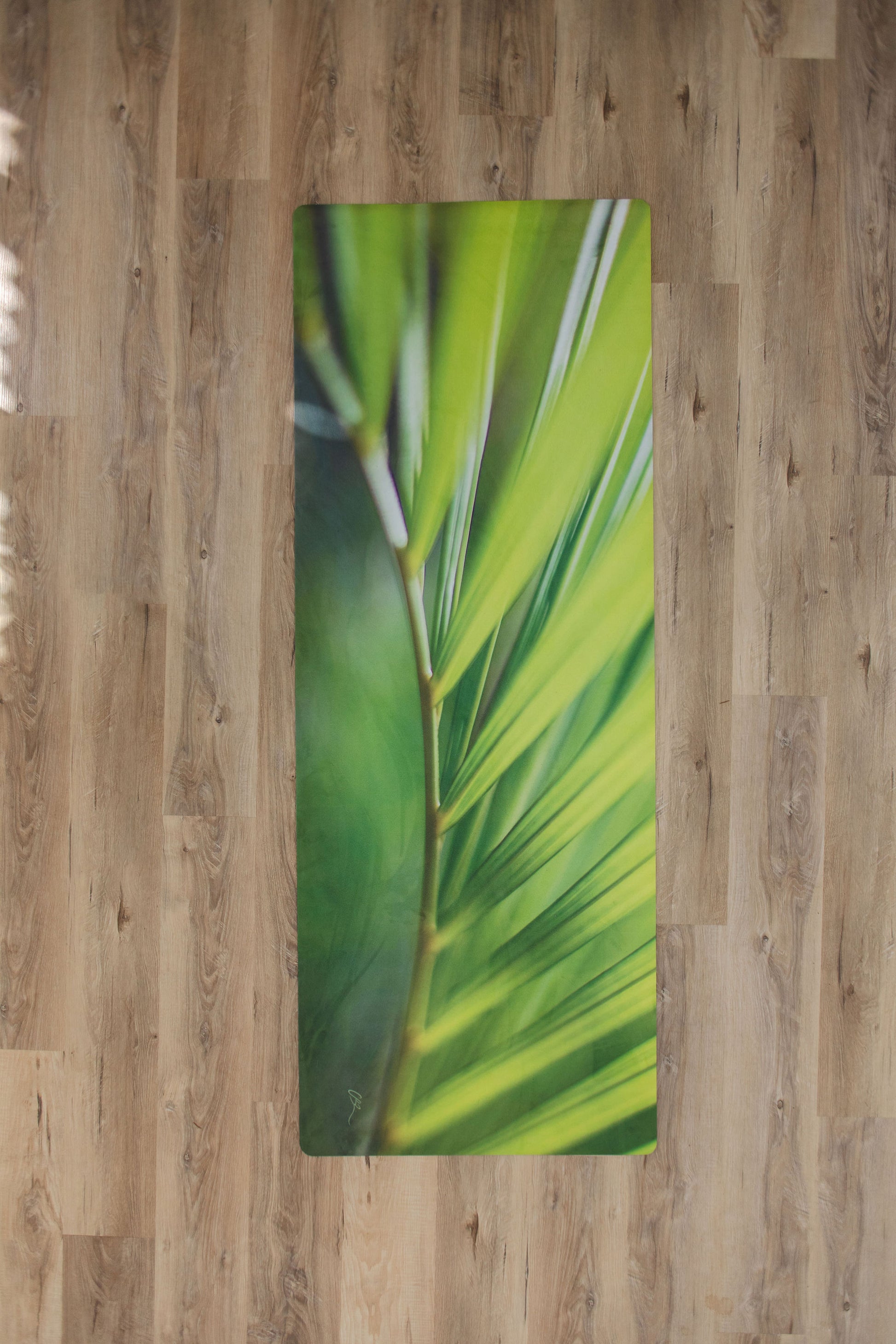 Yoga mat with green leaf design on a wooden floor
