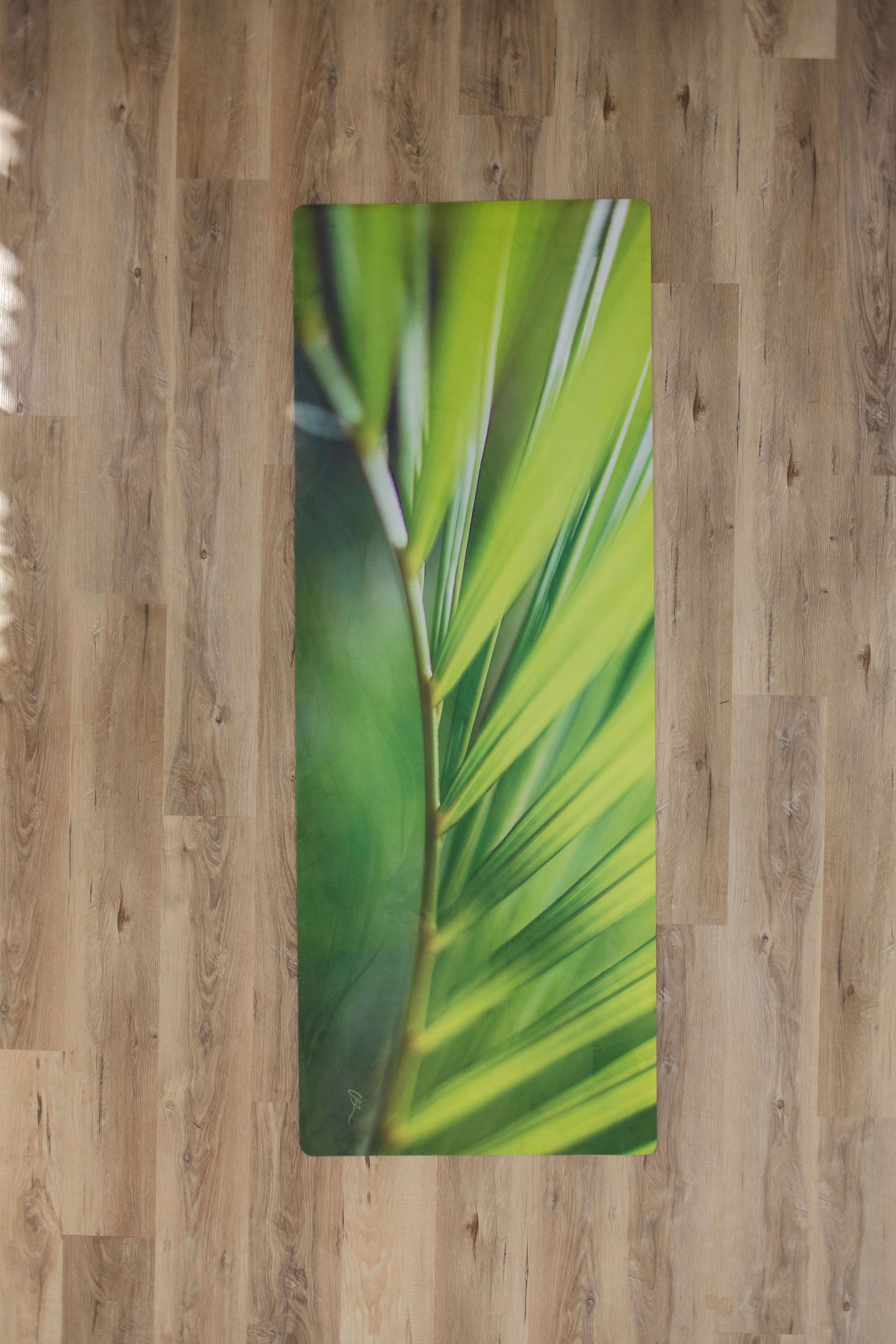 Yoga mat with green leaf design on a wooden floor