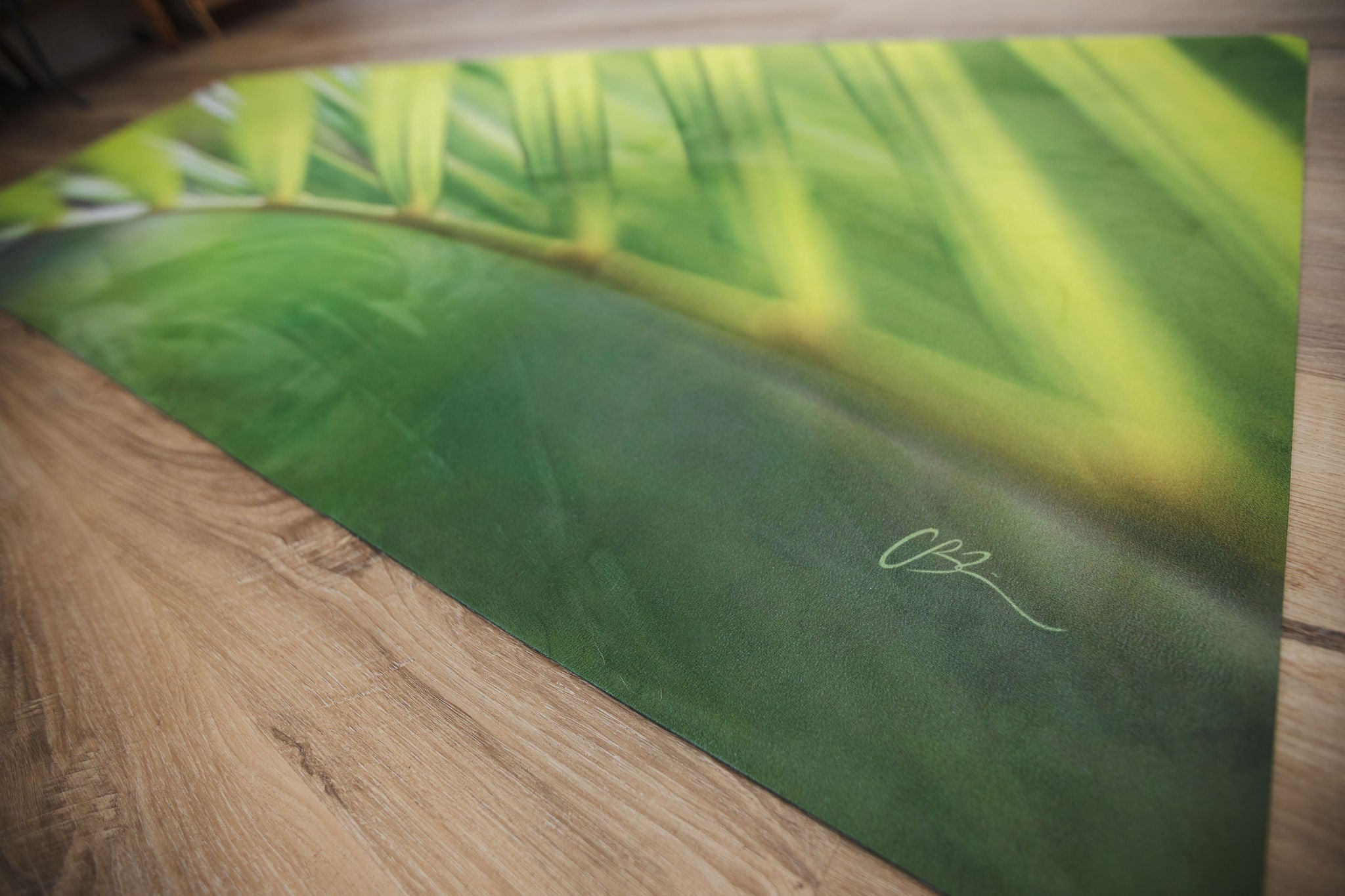 Yoga mat with green leaf design on a wooden floor