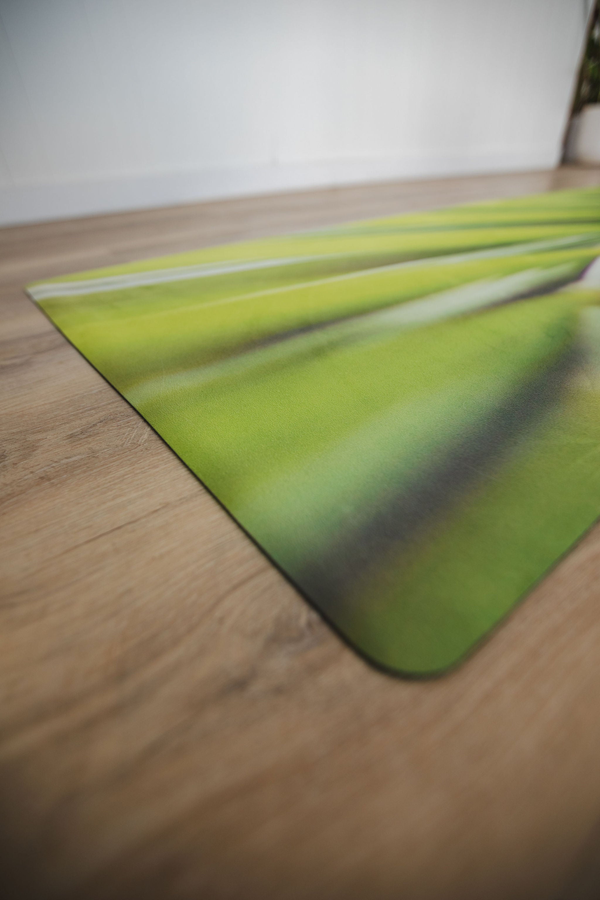 Yoga mat with green leaf design on a wooden floor