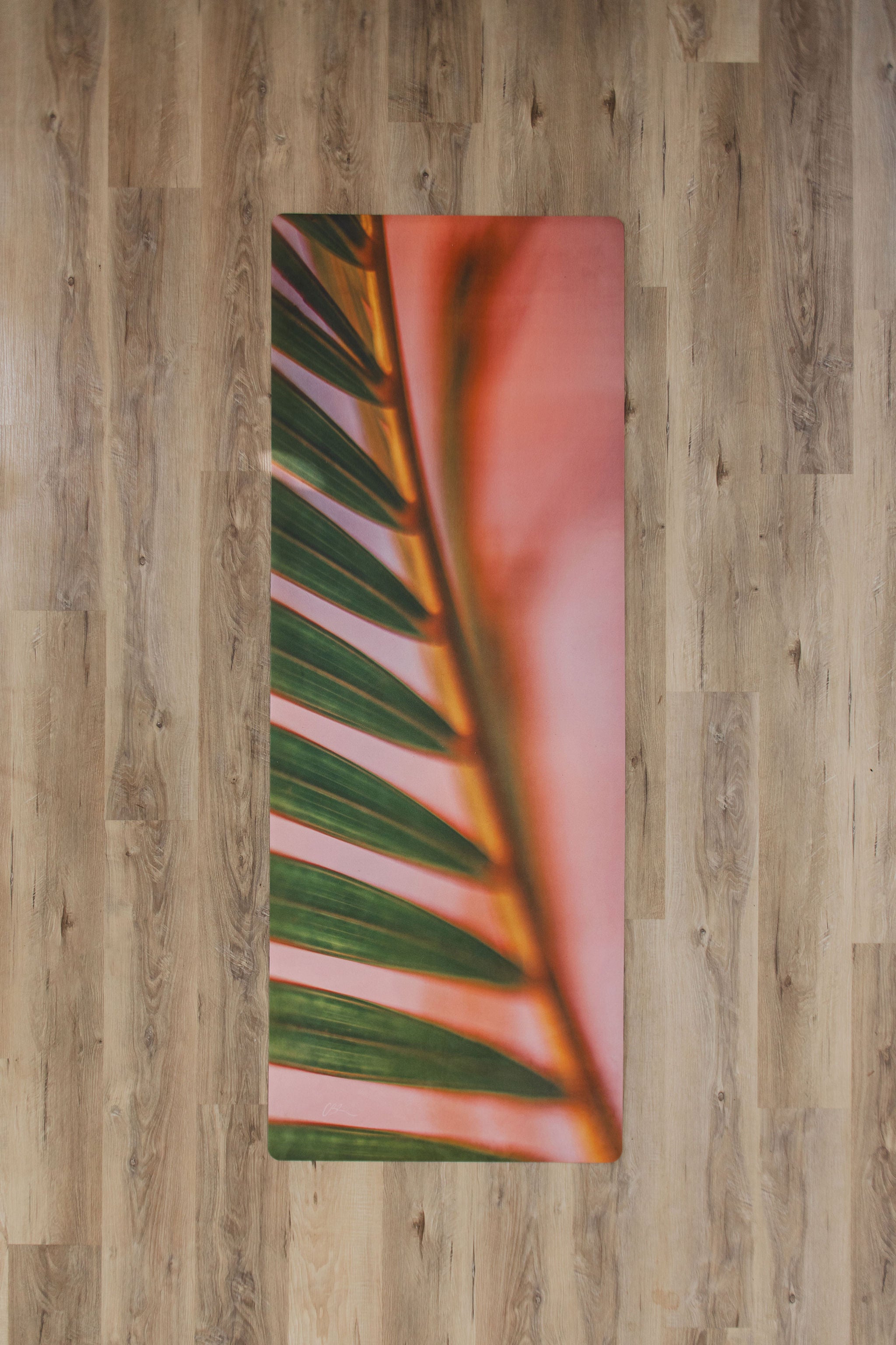 Yoga mat with green leaf design on a wooden floor