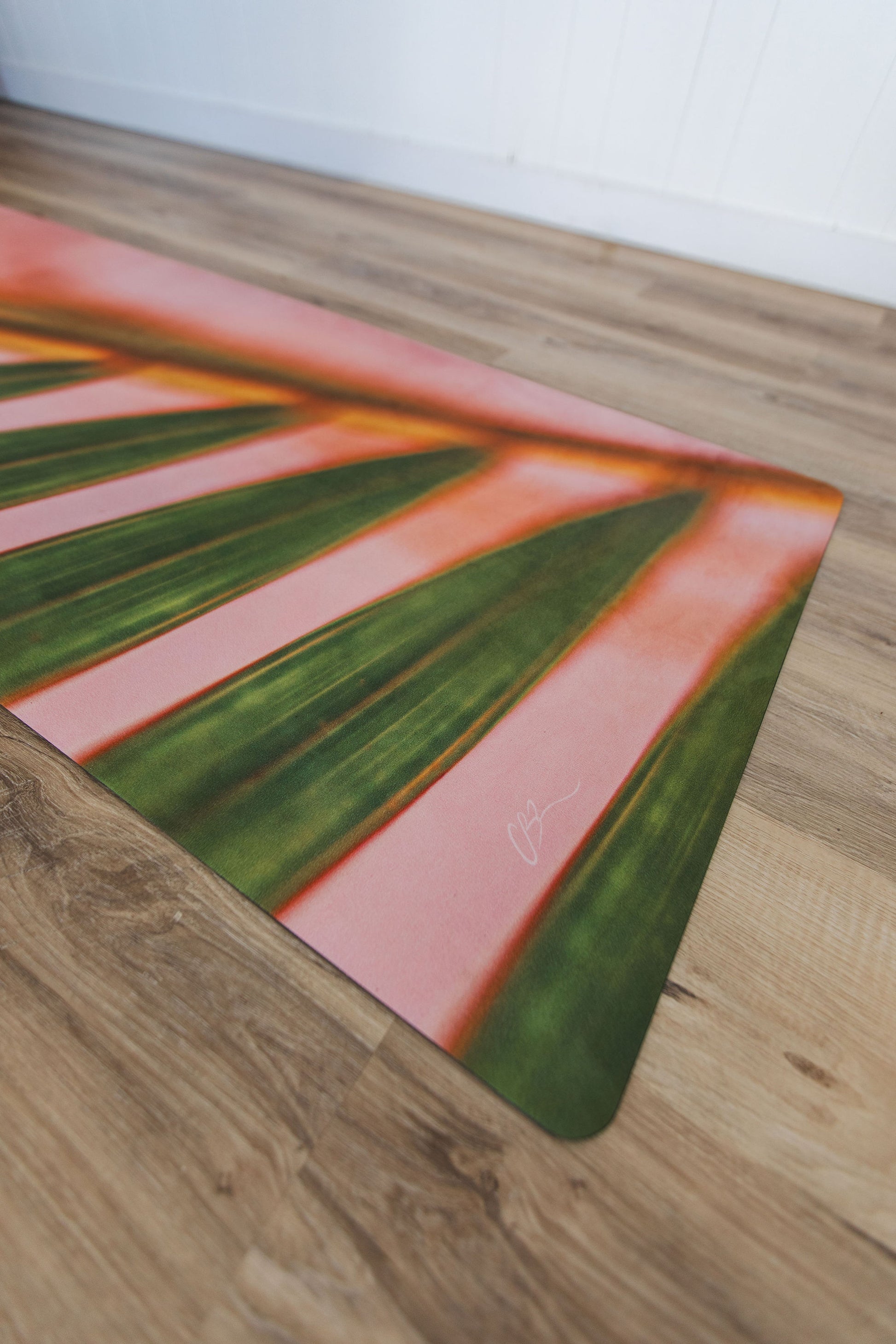 Pink and green yoga mat on a wooden floor