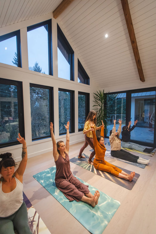 Group of people practicing yoga in a modern indoor setting with large windows.