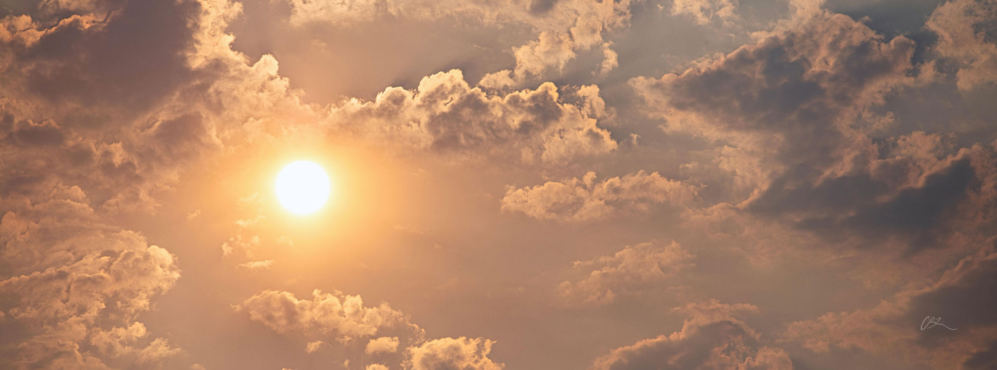 Sun setting behind clouds with a warm glow