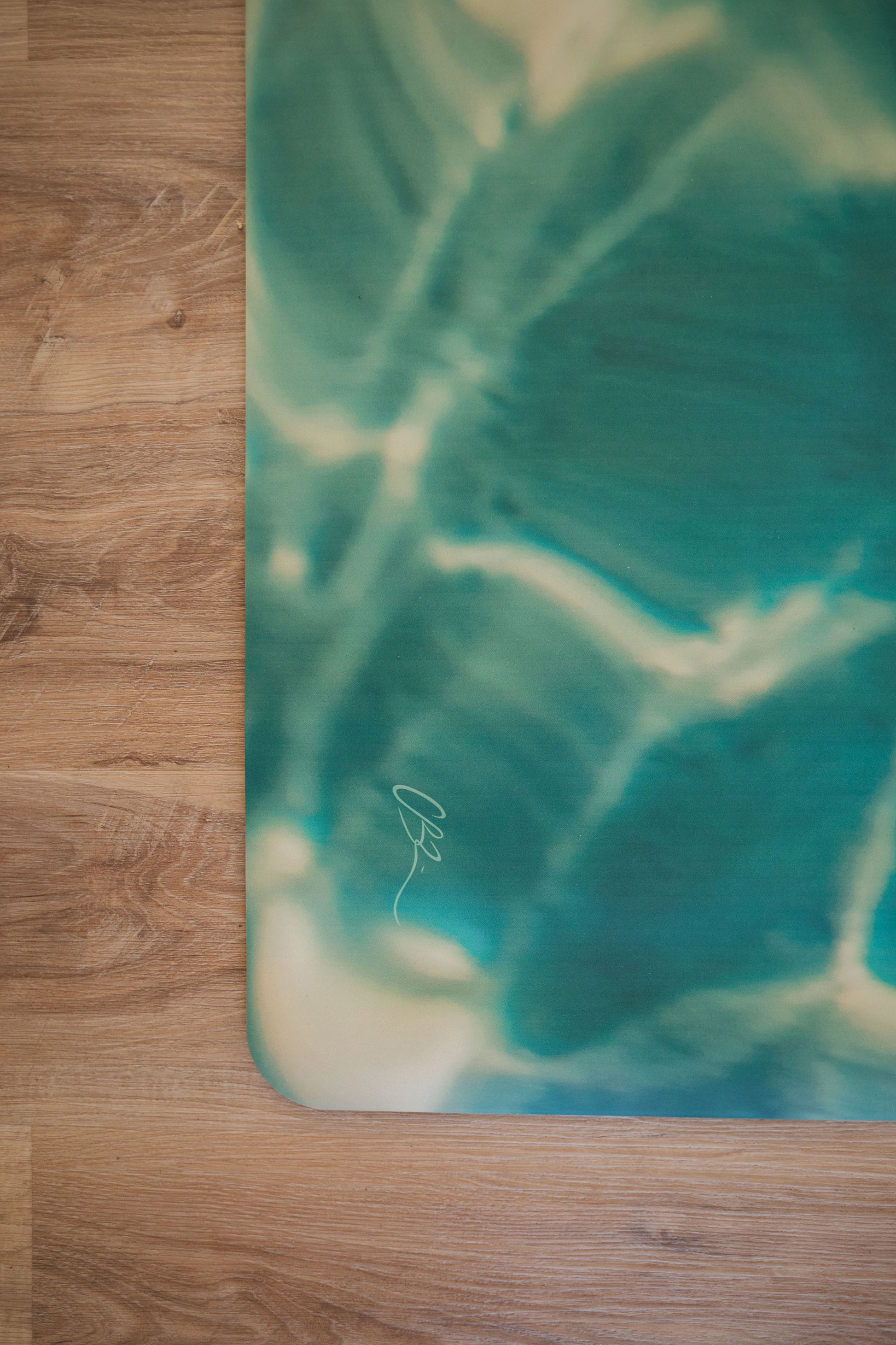Yoga mat with a green and blue abstract design on a wooden floor