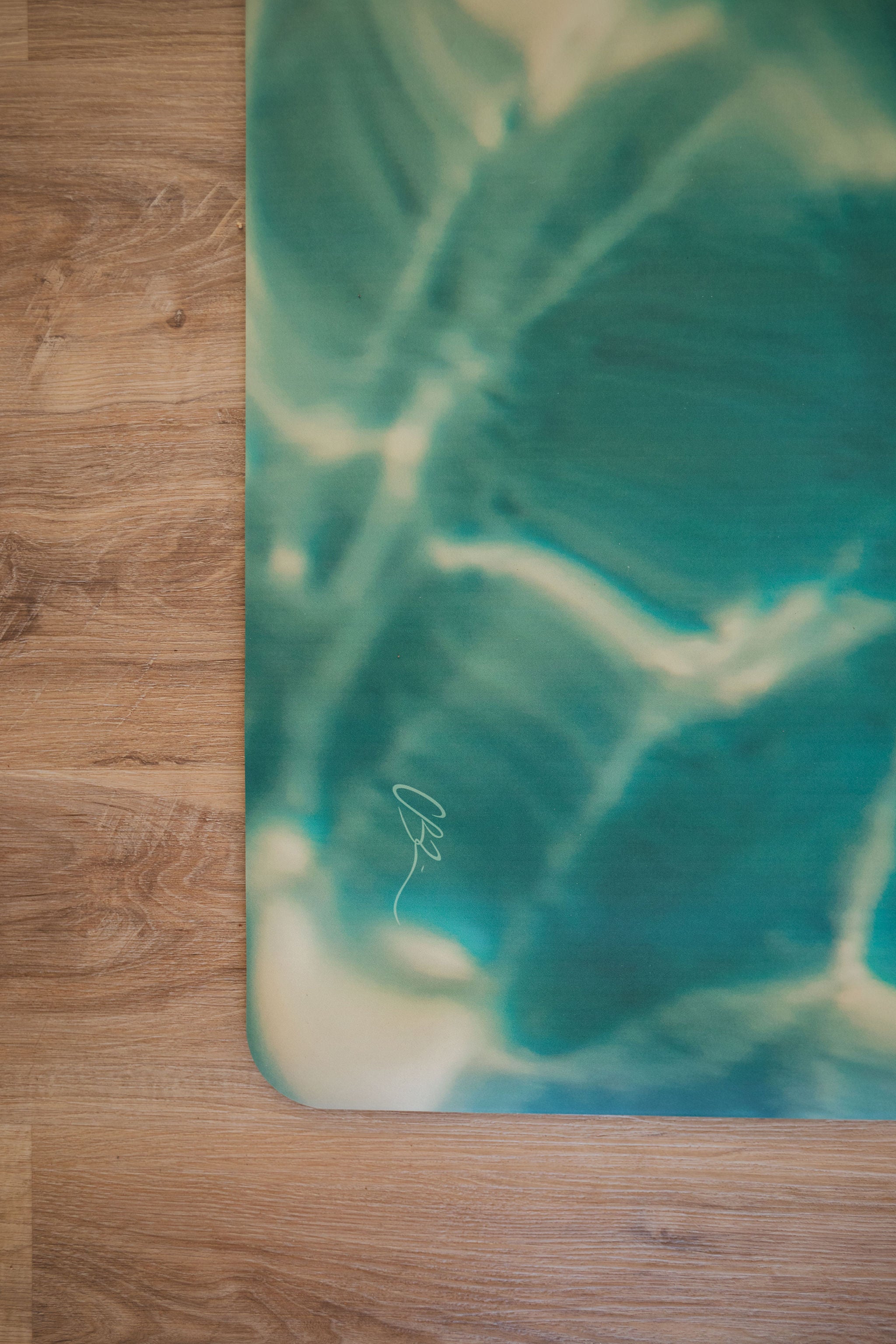 Yoga mat with a green and blue abstract design on a wooden floor