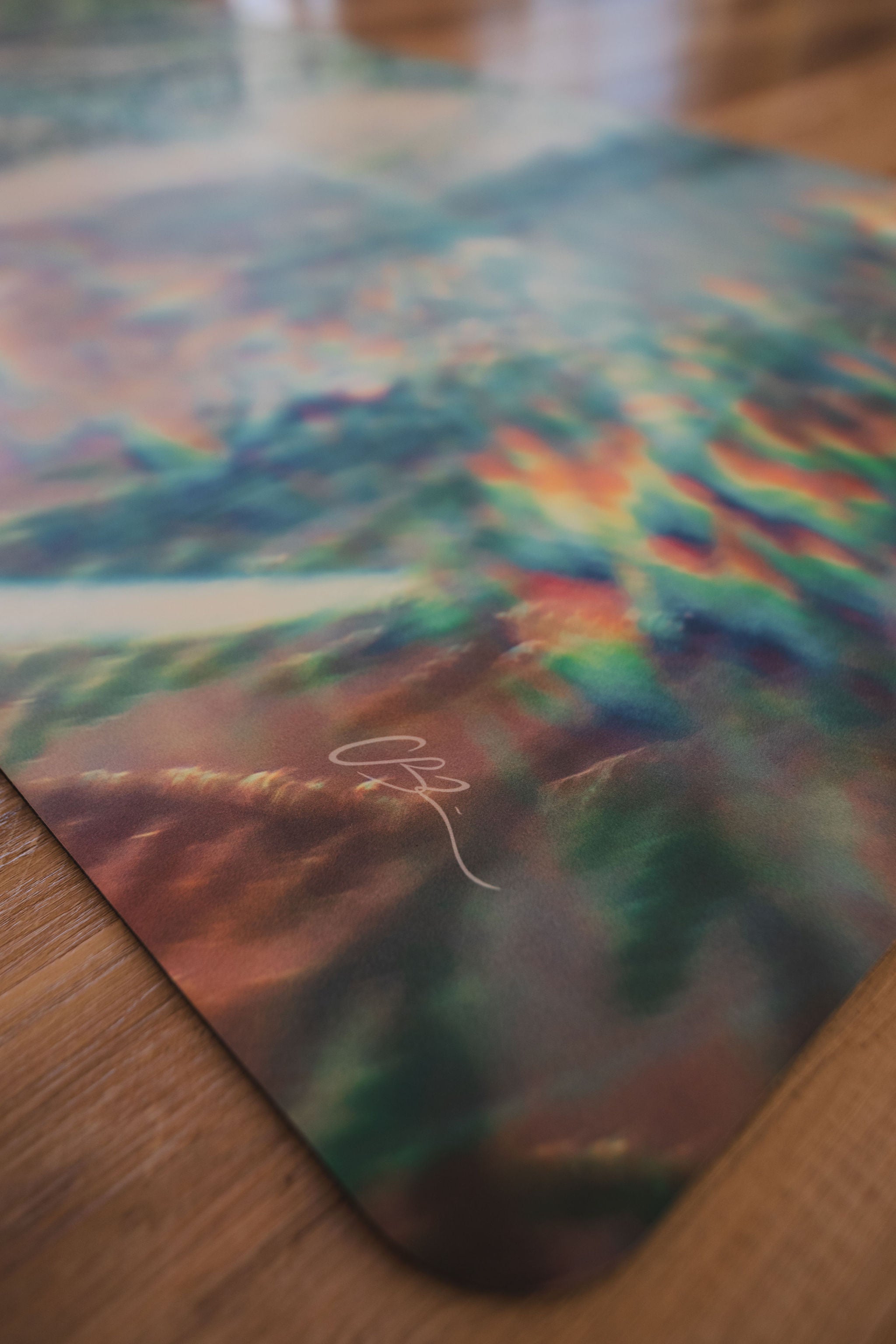 Colorful tie-dye pattern on a mat with a signature, on a wooden surface.