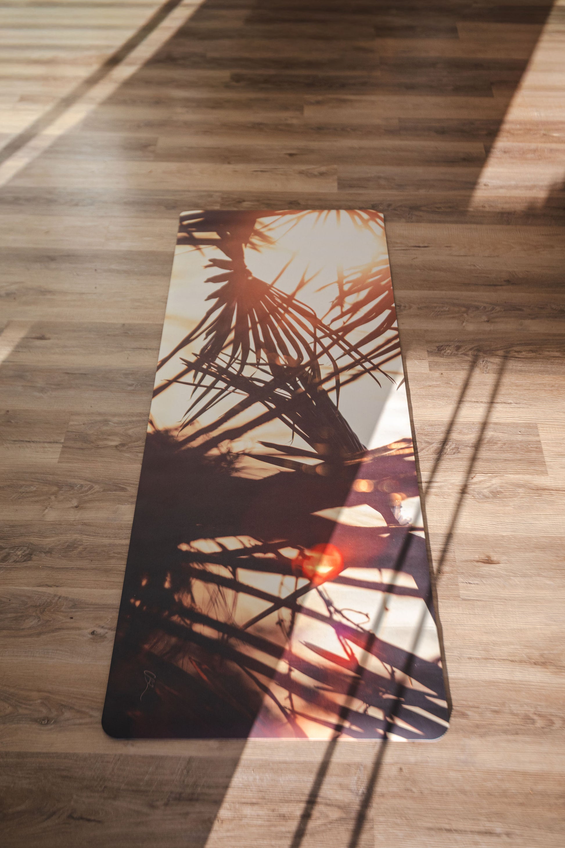 Yoga mat with palm leaf design on a wooden floor