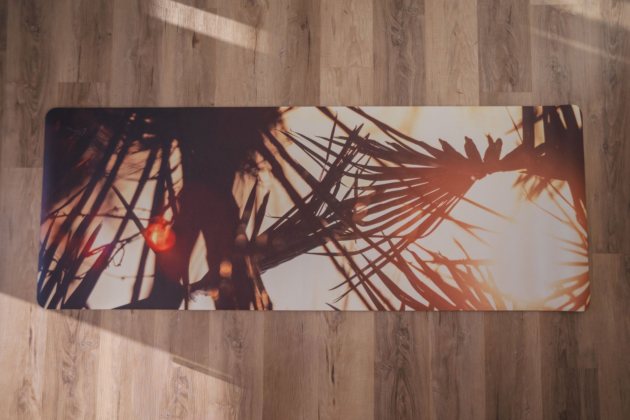 Yoga mat with palm leaf design on a wooden floor