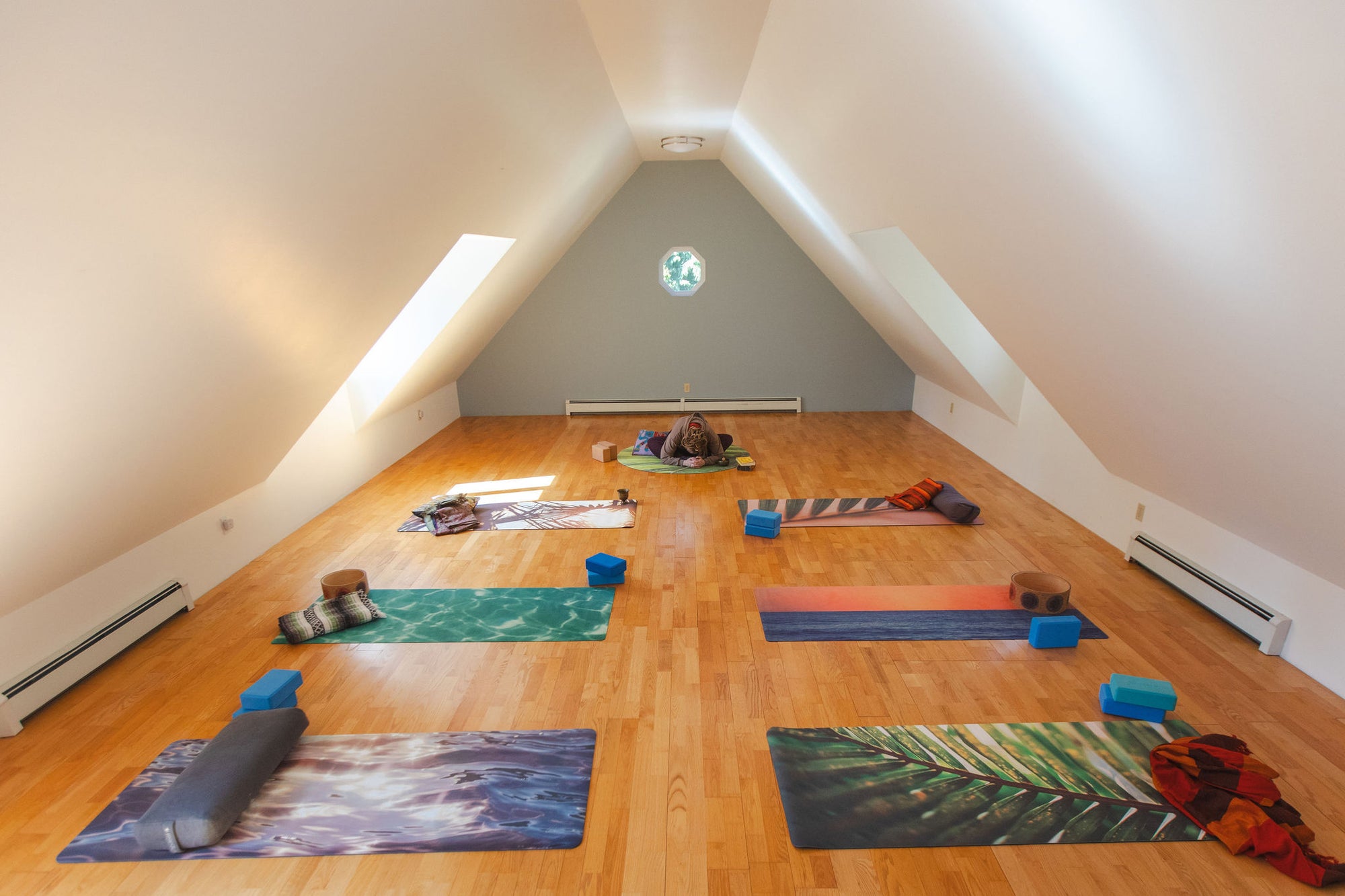 Yoga mats arranged on a wooden floor in a room with slanted ceiling
