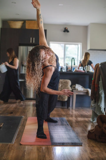 Person practicing yoga in a home setting with kitchen activities in the background
