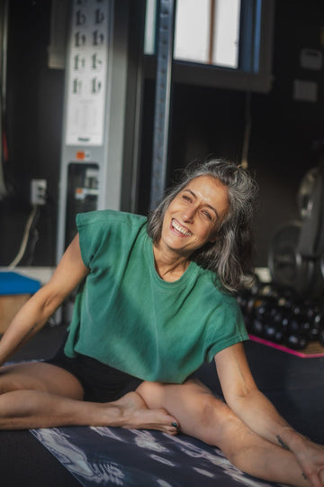 Woman in green shirt stretching in a gym setting