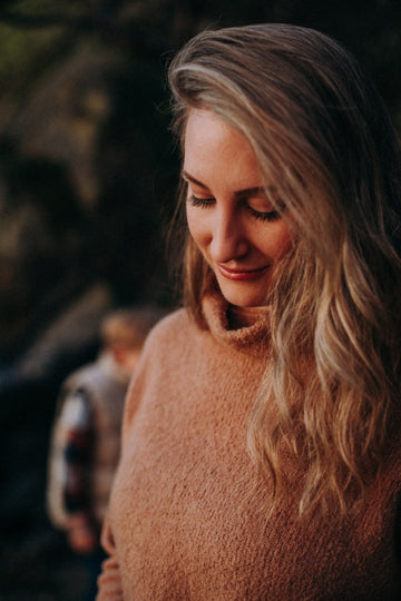 Woman wearing a brown sweater with a blurred background
