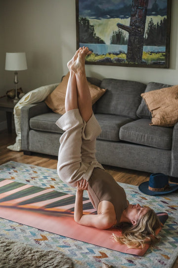 Person doing a handstand on a yoga mat in a living room.